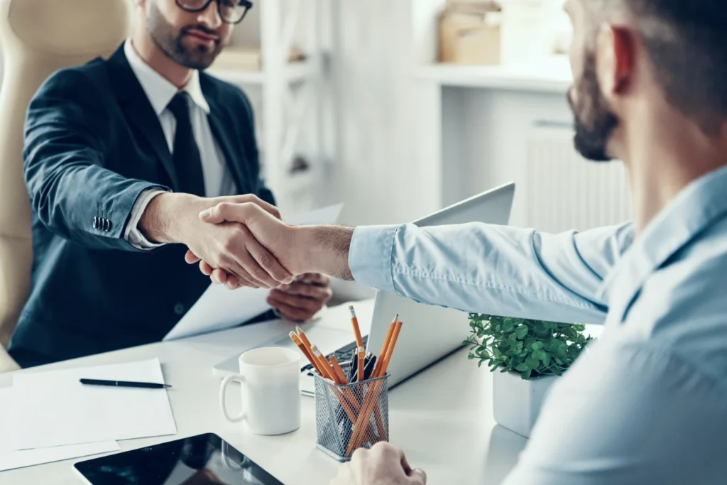 two men shaking hands at a desk
