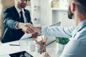 two men shaking hands at a desk
