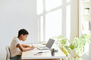 kid writing on a notebook on a desk
