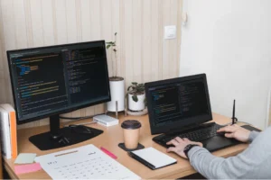 A person sitting at a desk with two computer monitors