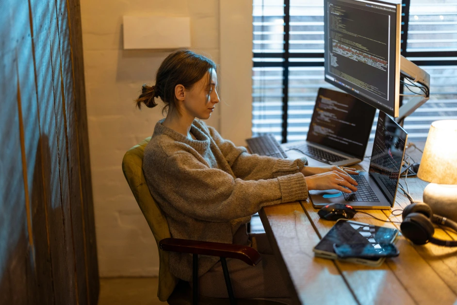 three women sitting at a desk working on laptops