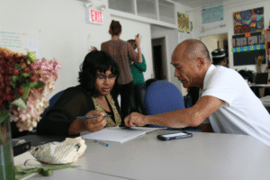 female student and male teacher sitting at desk learning
