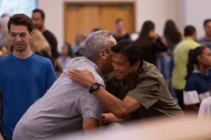 two men smiling embracing hugging at networking event