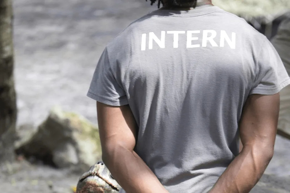 man standing wearing a shirt that reads intern on the back