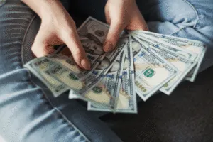 holds holding money fanning out one hundred dollar bills