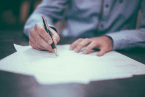 man signing an offer letter while sitting at a desk