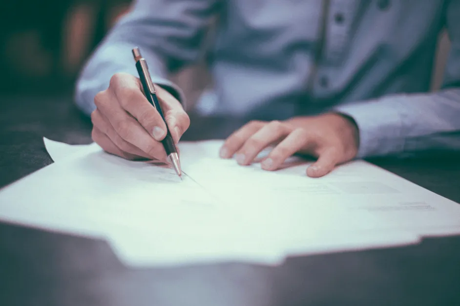 man signing an offer letter while sitting at a desk